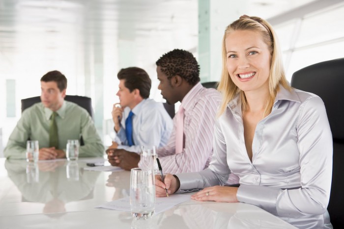 Four businesspeople in a boardroom smiling